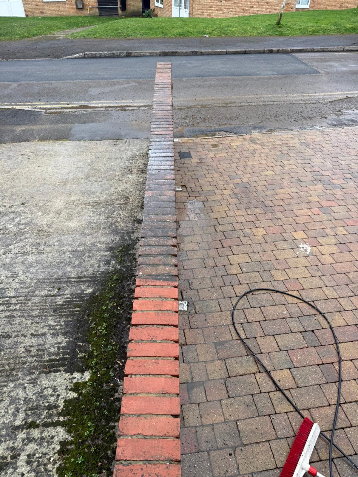 Driveway paving half cleaned showing the contrast between dirty and jet washed areas