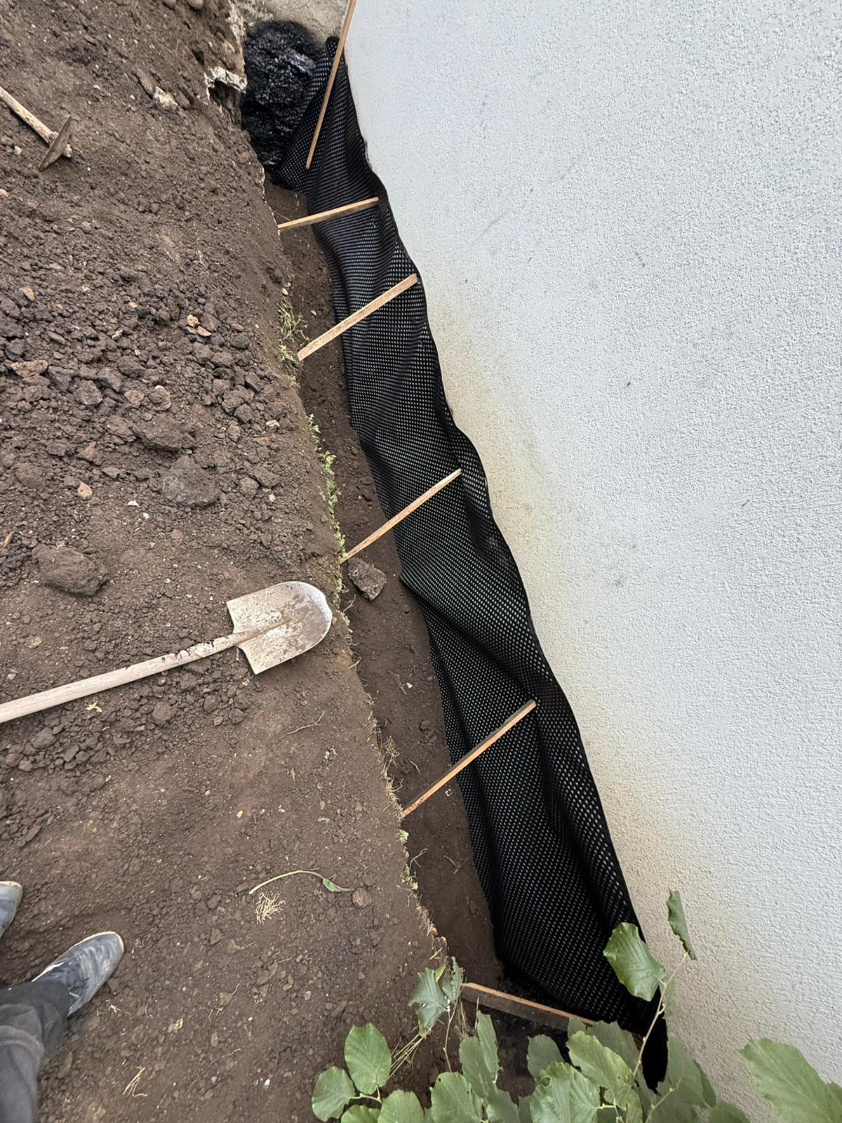Drainage membrane secured to the wall along the trench