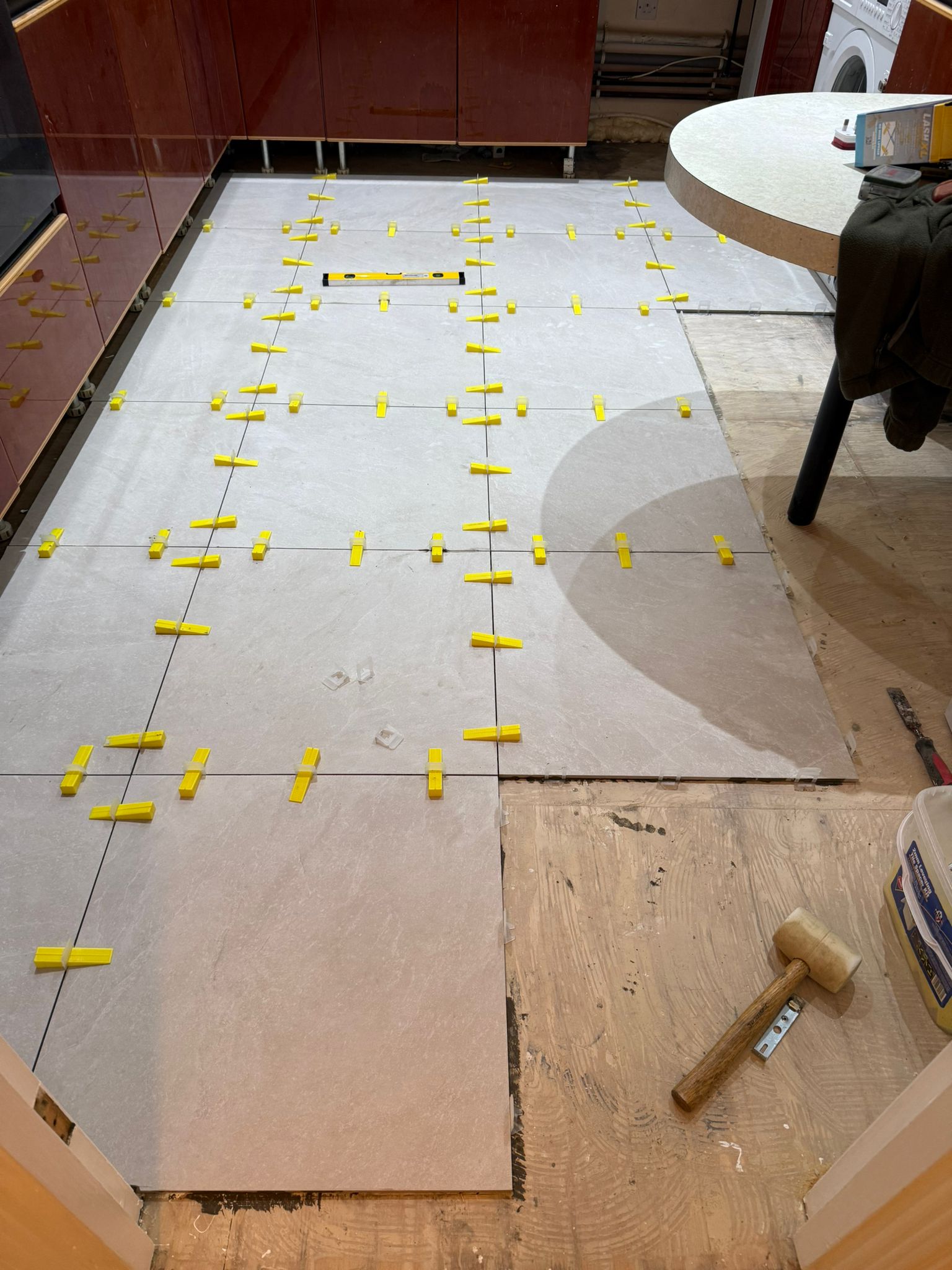 New kitchen floor tiles being aligned and levelled during installation